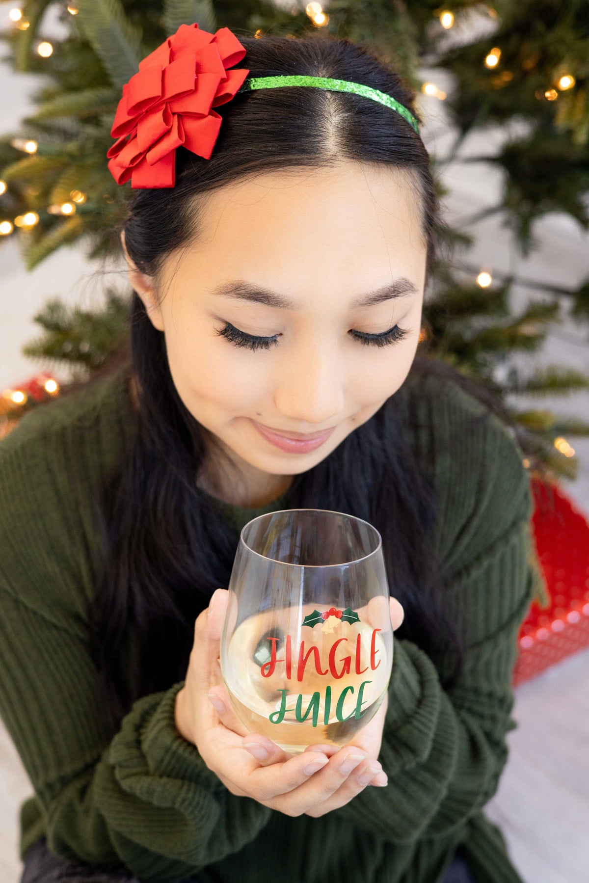 Pearhead festive Jingle Juice Christmas stemless wine glass — woman sipping from Jingle Juice glass
