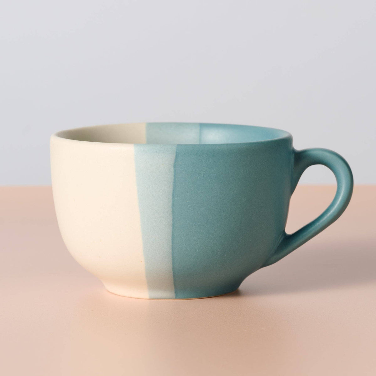 Ten Thousand Villages ceramic blue-and-cream 20oz mug with spoon, angled view