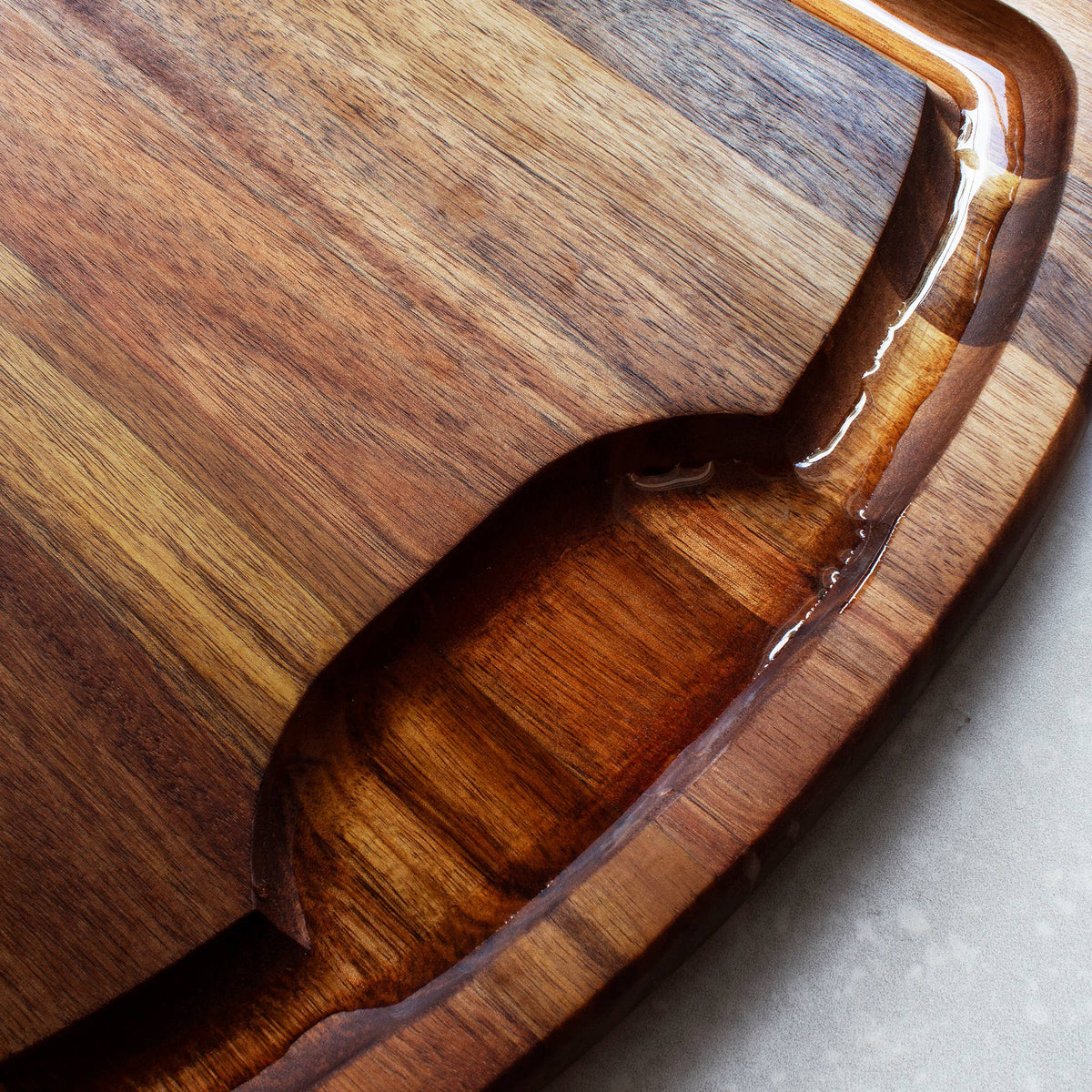Totally Bamboo Rock & Branch® Acacia Wood Carving Board with Juice Groove: cutting board styled on a counter