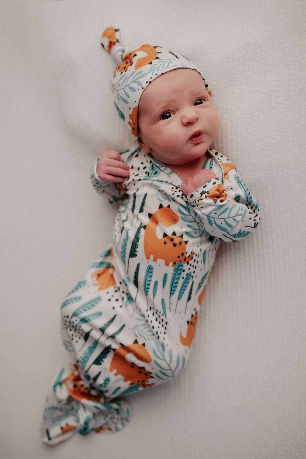 Three Little Tots - Dinosaur Animal Print Zoo Knotted Gown — baby wearing dinosaur print knotted gown