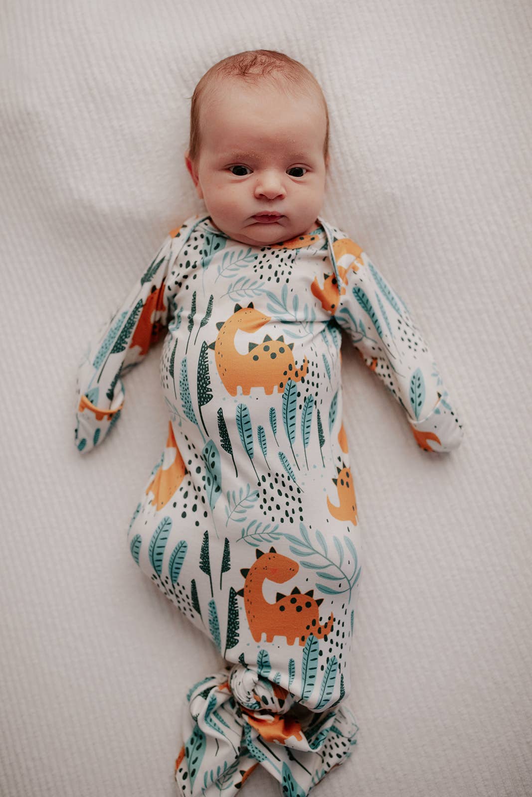 Three Little Tots - Dinosaur Animal Print Zoo Knotted Gown — baby wearing dinosaur print knotted newborn gown