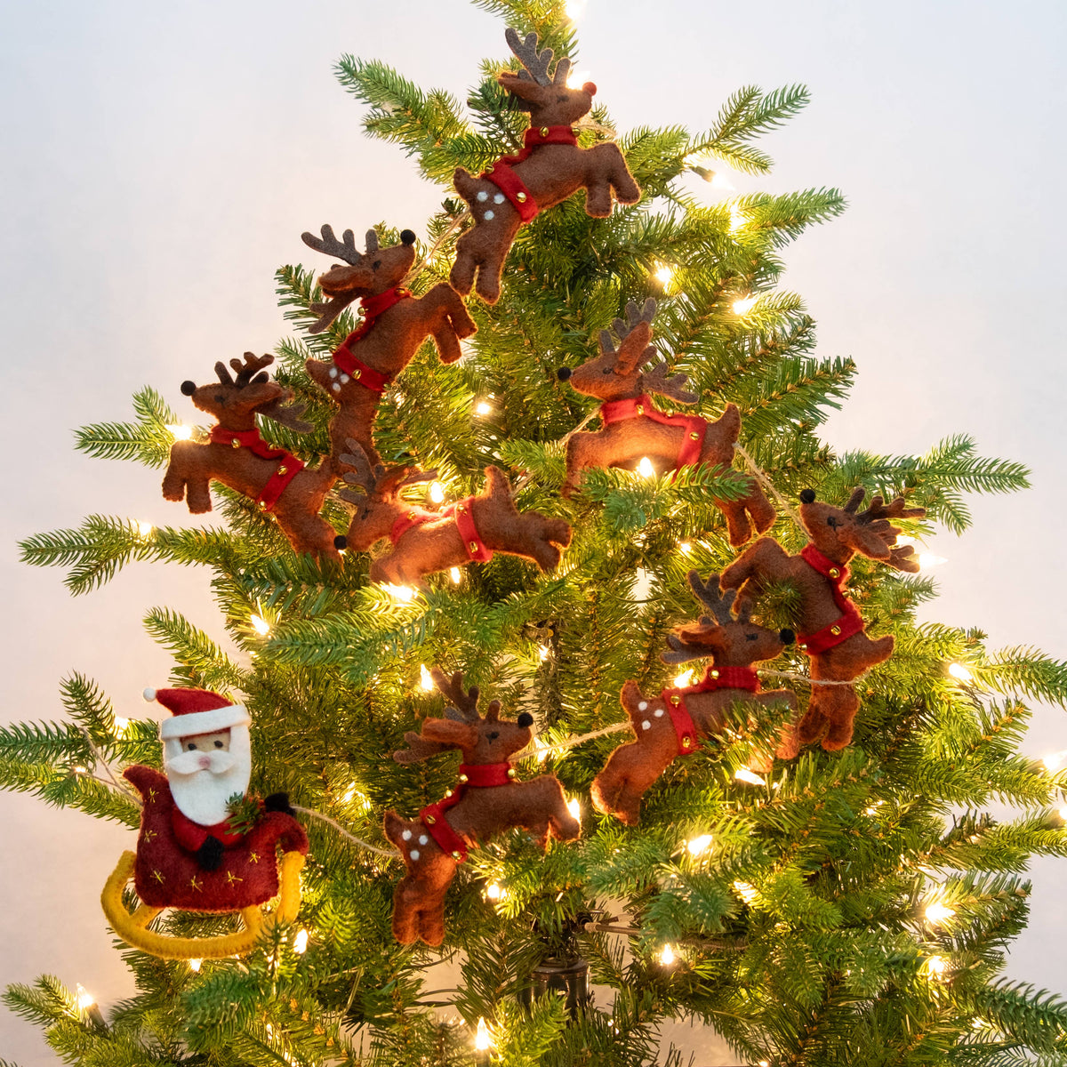 The Winding Road - Garland - Christmas - Santa Sleigh and 8 Reindeer - Brown — felt Christmas garland draped on evergreen tree