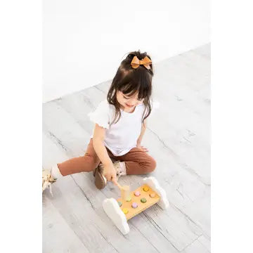 Pearhead FSC-certified wooden toddler hammer bench toy, young girl playing wooden pounding toy on floor