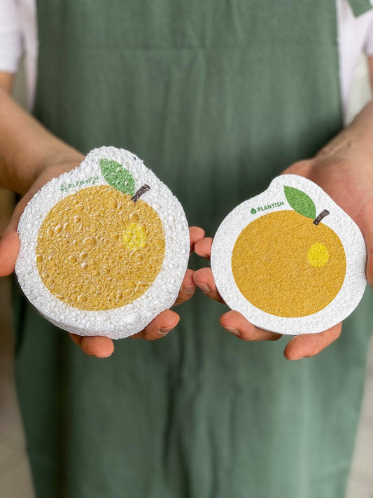 Plantish plastic-free compostable orange cellulose sponge, hands holding two orange-shaped cellulose sponges