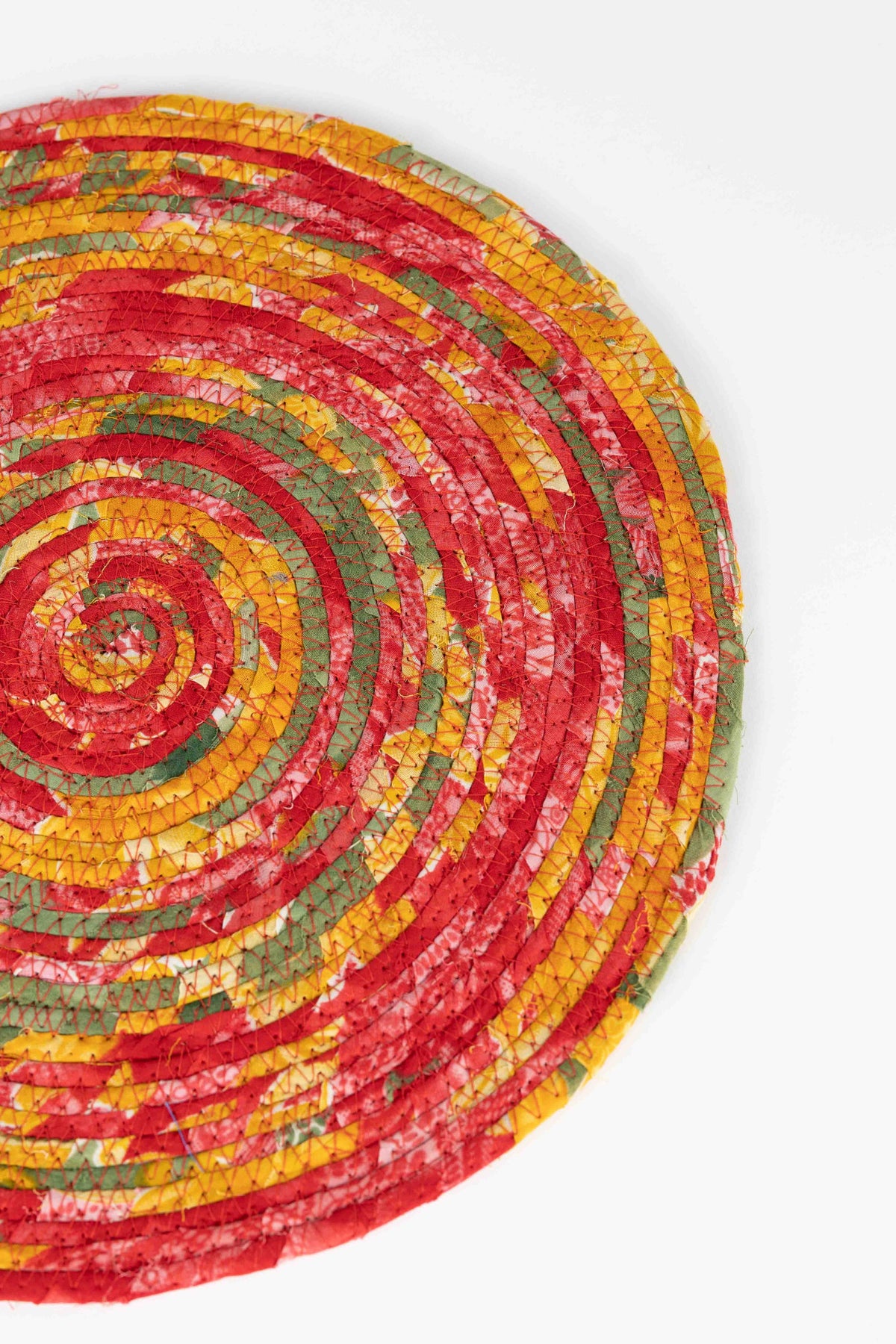 Ten Thousand Villages Recycled Sari Round Placemat: side angle showing shape and surface; recycled sari fabric