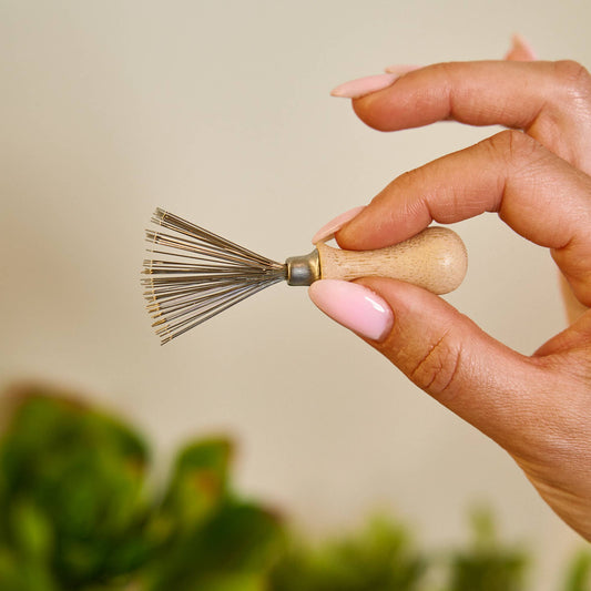Bamboo Switch reusable bamboo hairbrush cleaning tool: fan of metal teeth held between fingers