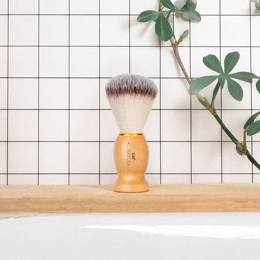 J&L Naturals vegan bamboo-handled shaving brush, bamboo-handle shaving brush with pale bristles on bathroom shelf