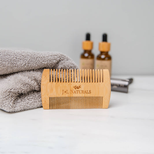 J&L Naturals sustainable bamboo beard comb — wooden dual-sided comb with beard-care products on bathroom counter
