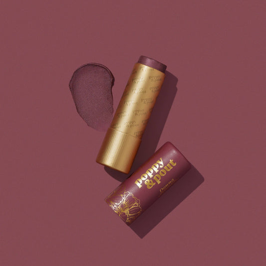 Poppy & Pout Donna beeswax lip tint — plum lip tint tube and gold cap on burgundy background