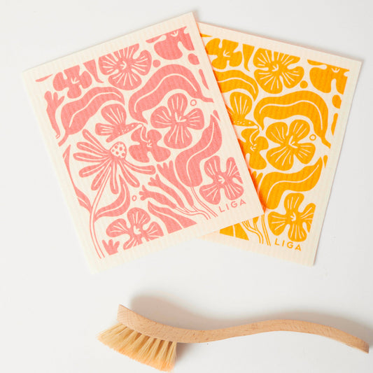 LIGA Eco Dishcloth - Flora - two peach and yellow floral dishcloths beside bamboo brush; FSC-certified cellulose