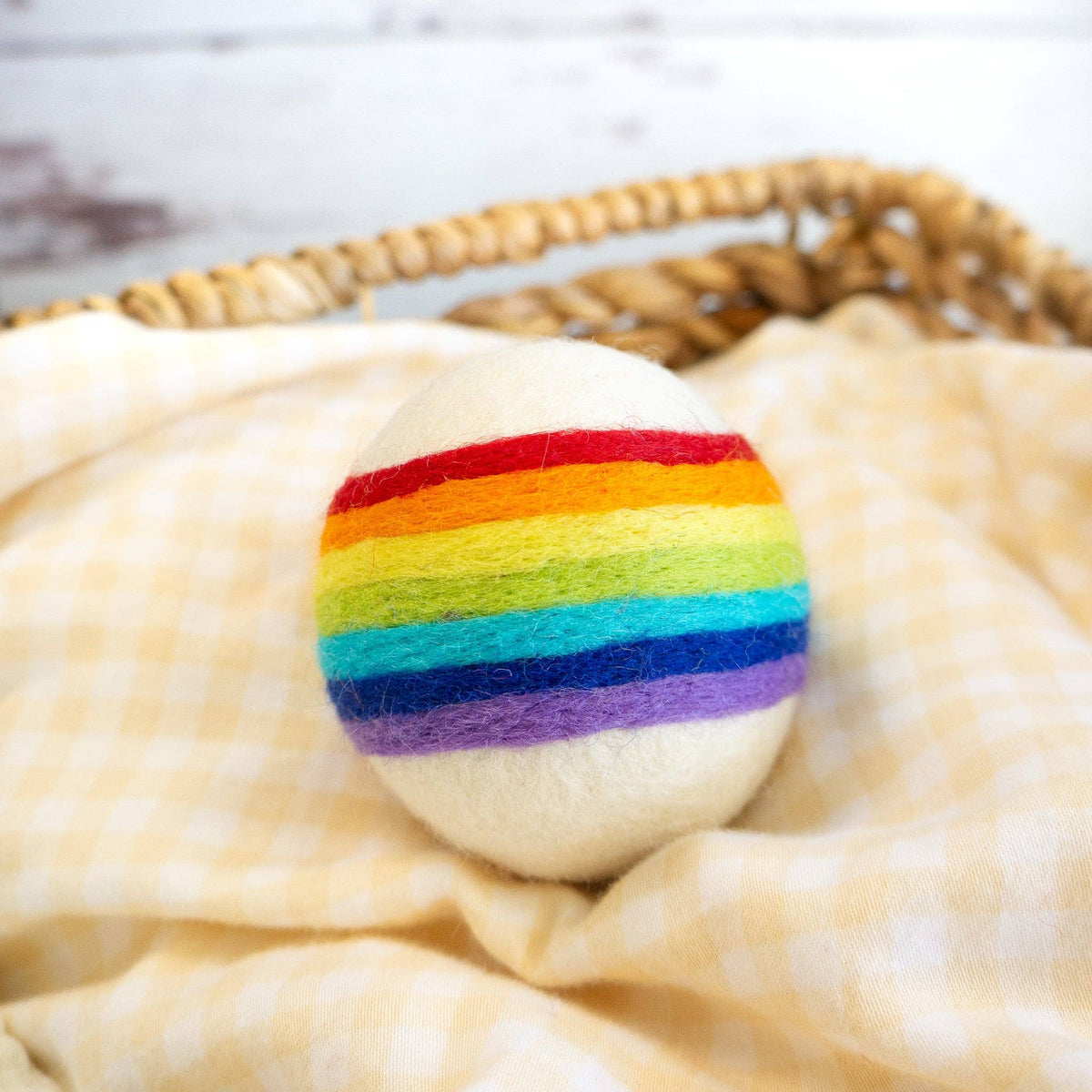 Friendsheep compostable rainbow wool dryer balls set of three: close-up of rainbow felt wool dryer ball in wicker basket