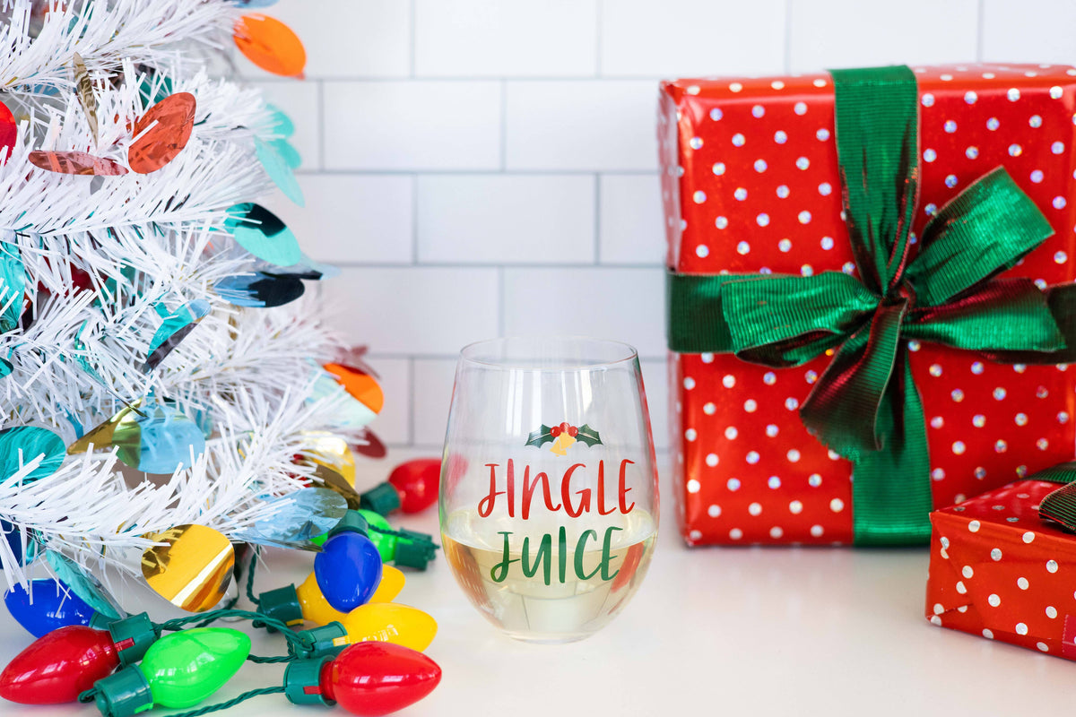Pearhead festive Jingle Juice Christmas stemless wine glass — wine glass beside wrapped holiday gifts
