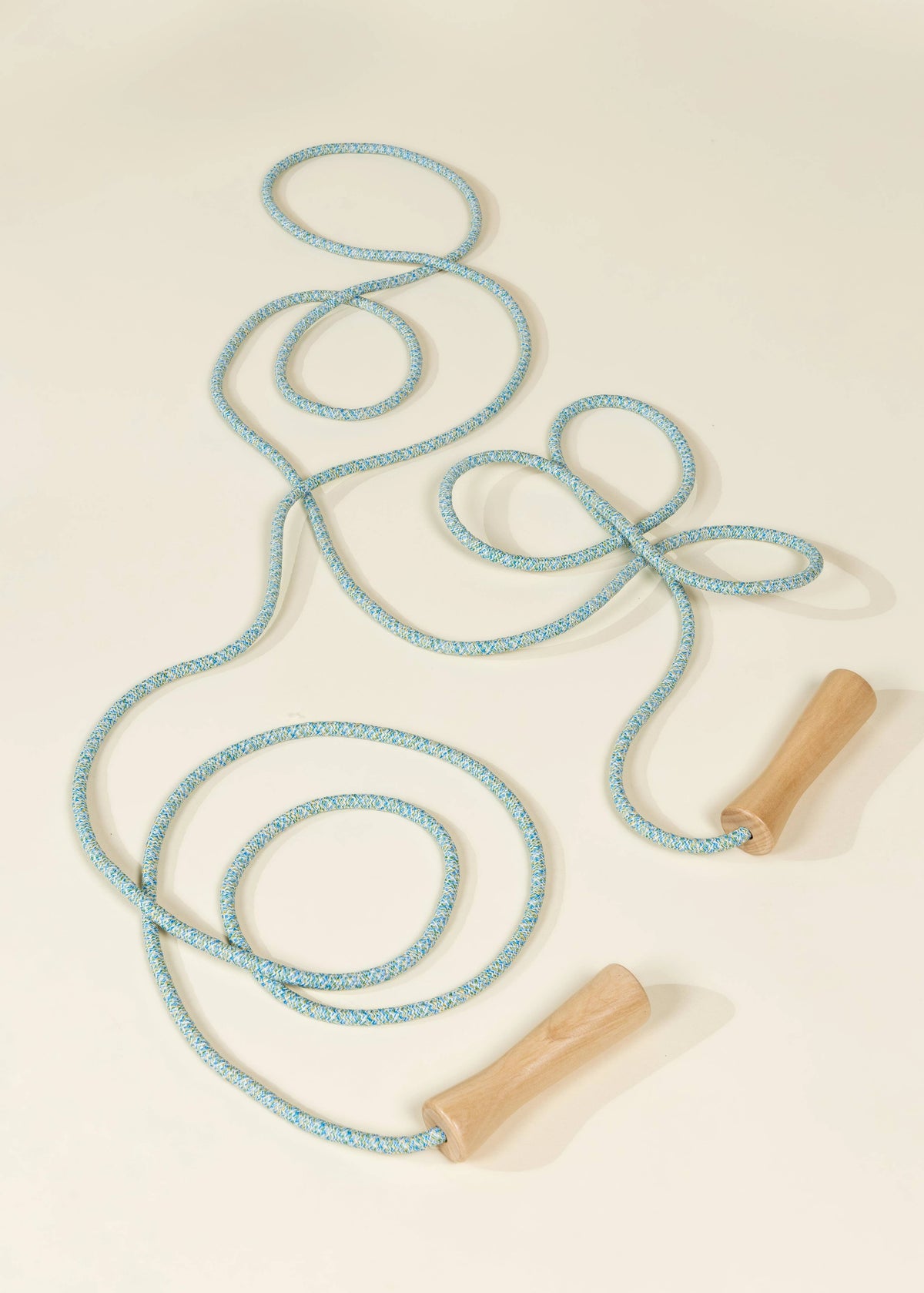 Coco Village blue rope with wooden jump handles, light blue skipping rope laid out in loops on cream background