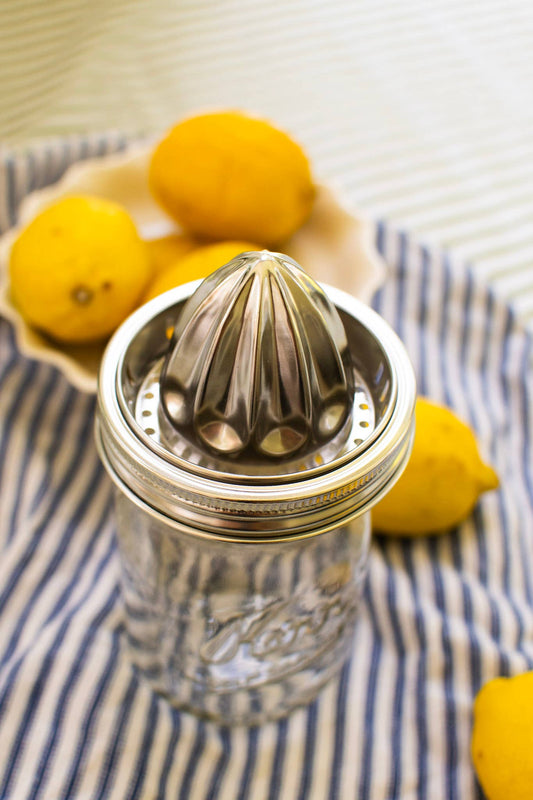 Zefiro reusable stainless steel citrus juicer fitted to a wide-mouth glass jar beside fresh lemons